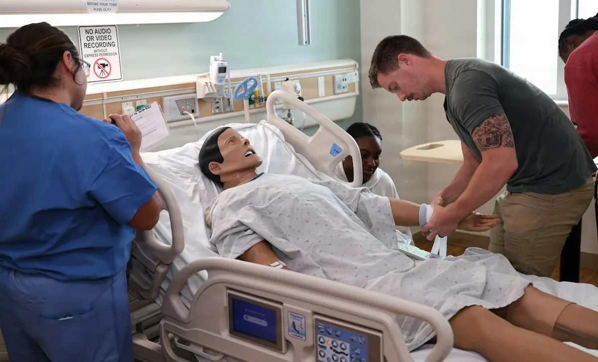 Nursing trainees practice care on a patient simulator in a hospital training room