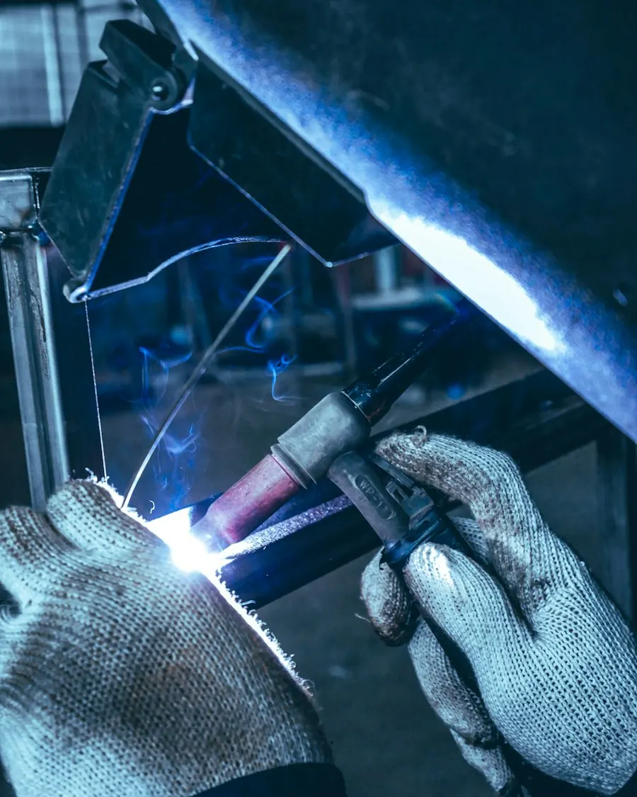 A welder's gloved hand guiding a torch, with a bright arc against the metal