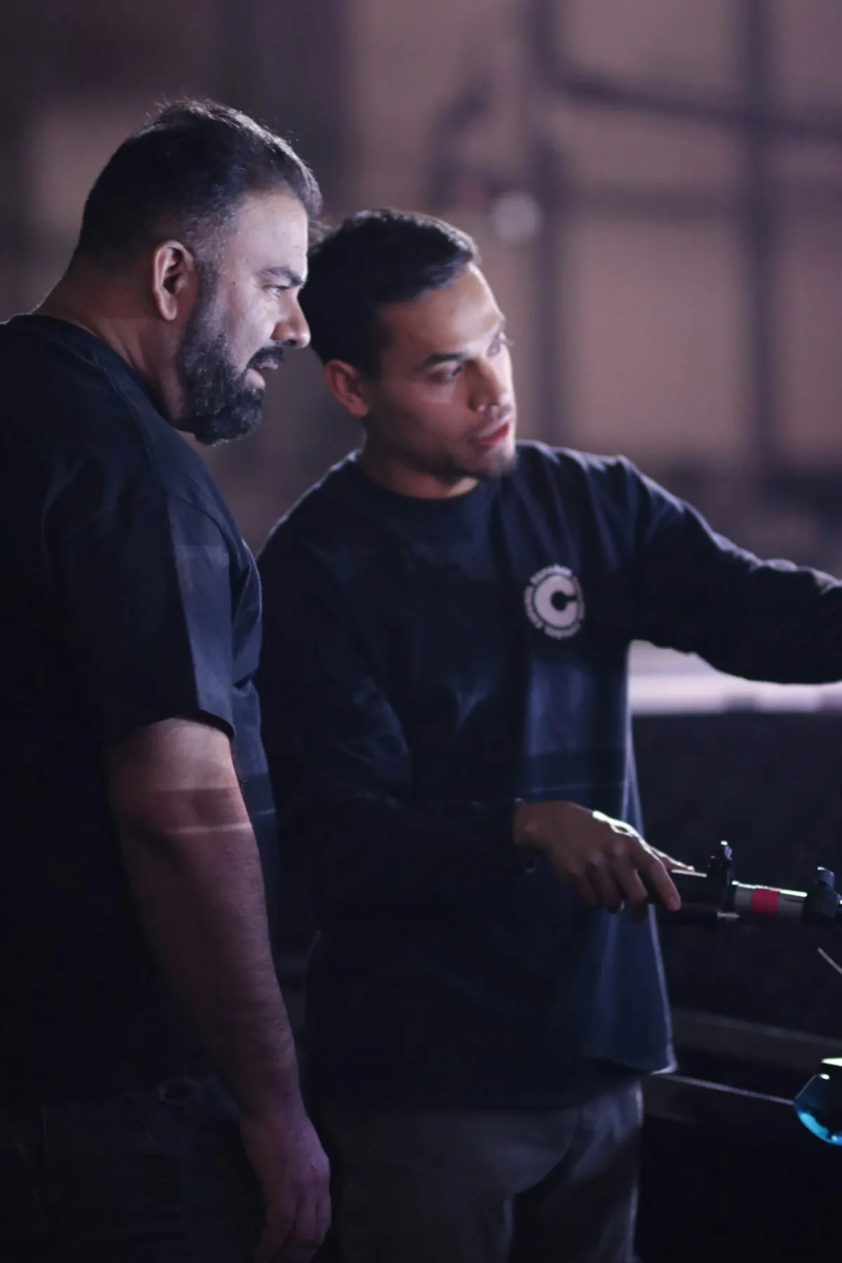 A more experienced worker explains a task to a younger colleague in a workshop
